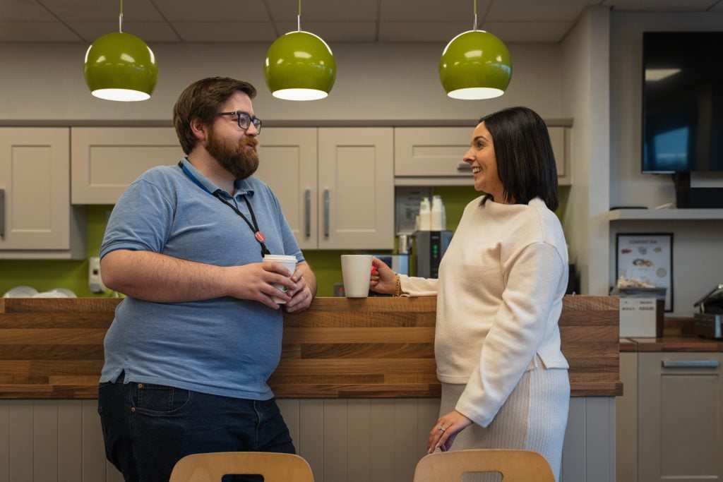 Two colleagues chatting over coffee at work
